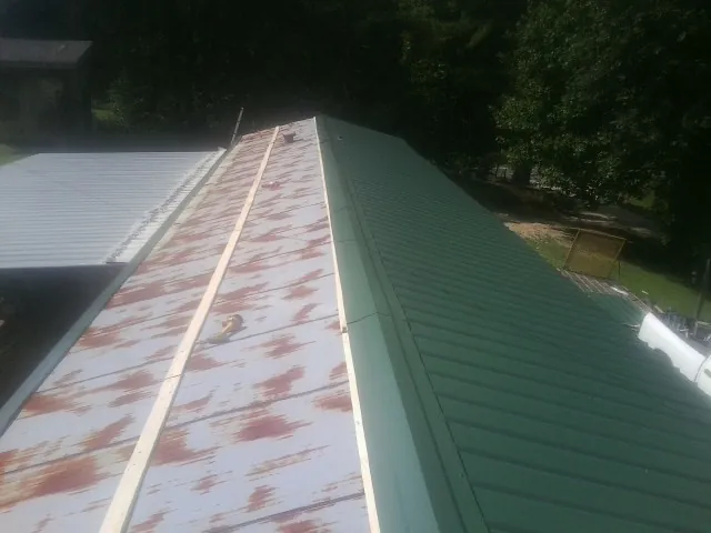 Old rusted panels beside newly installed green metal roofing — Wind Damage Roof Repair by Roofing Brothers in Hillrose