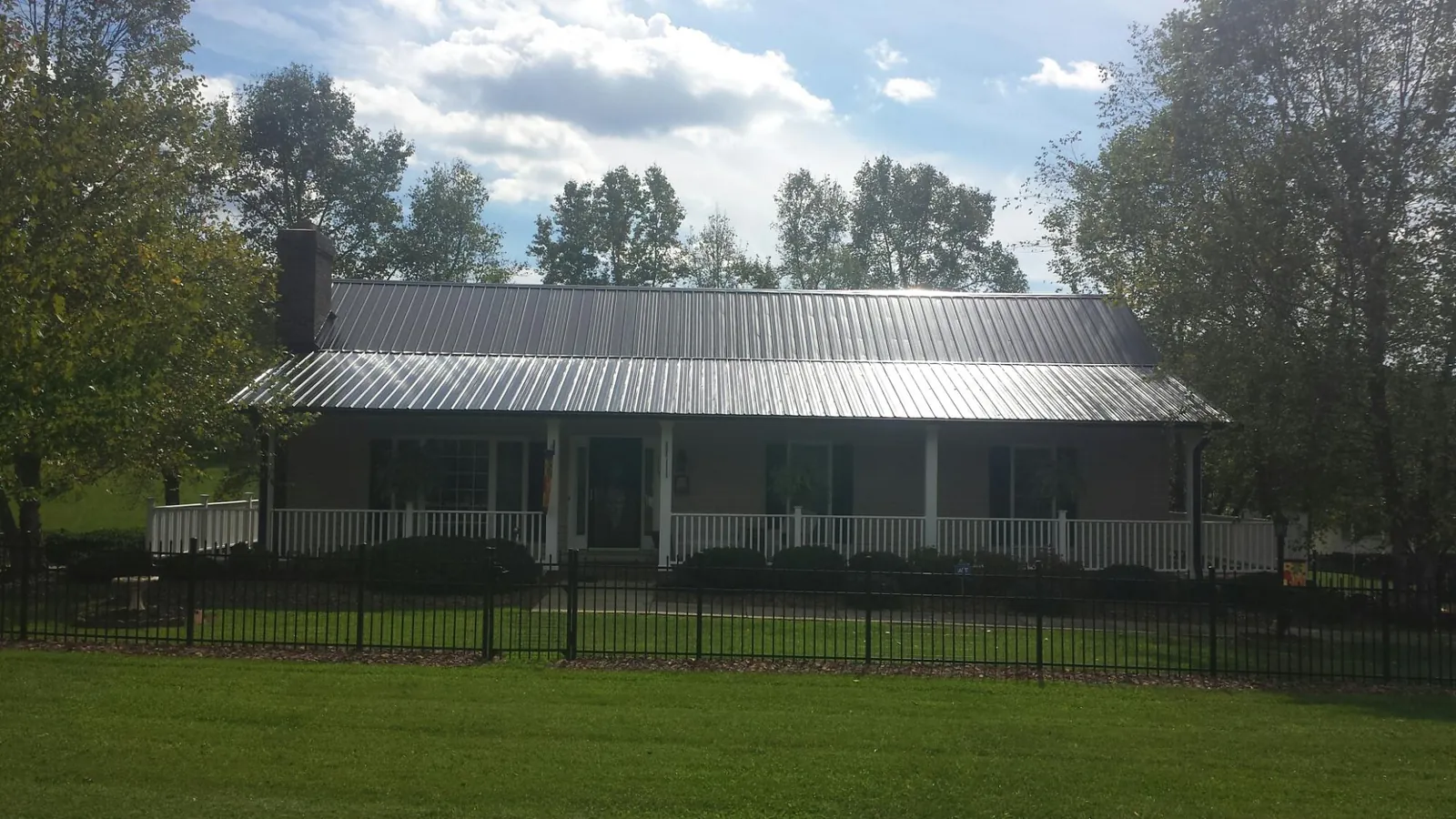 Gray metal roof on a brick ranch with a full width front porch — Gutter Guard Installation work by our crew in Hillrose