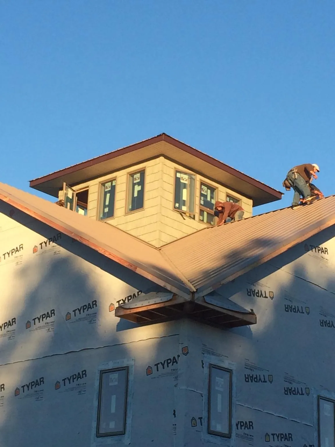 Roofers working around a rooftop cupola on a new metal roof at sunset — Roof Waterproofing in Hillrose by Roofing Brothers